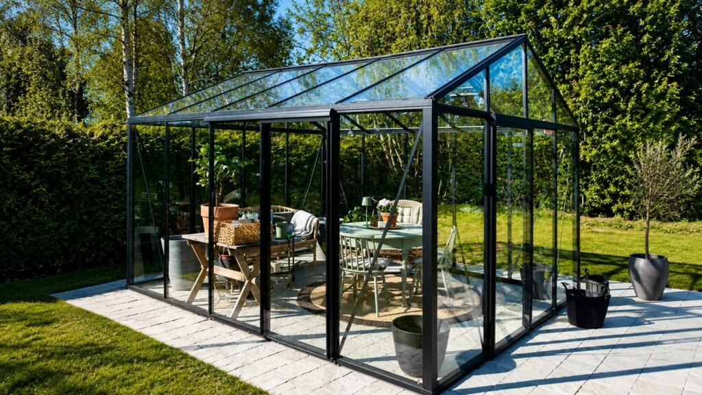 Bloomcabin Premium Classic aluminum greenhouse with tempered glass panels and modern sliding doors in a landscaped backyard garden