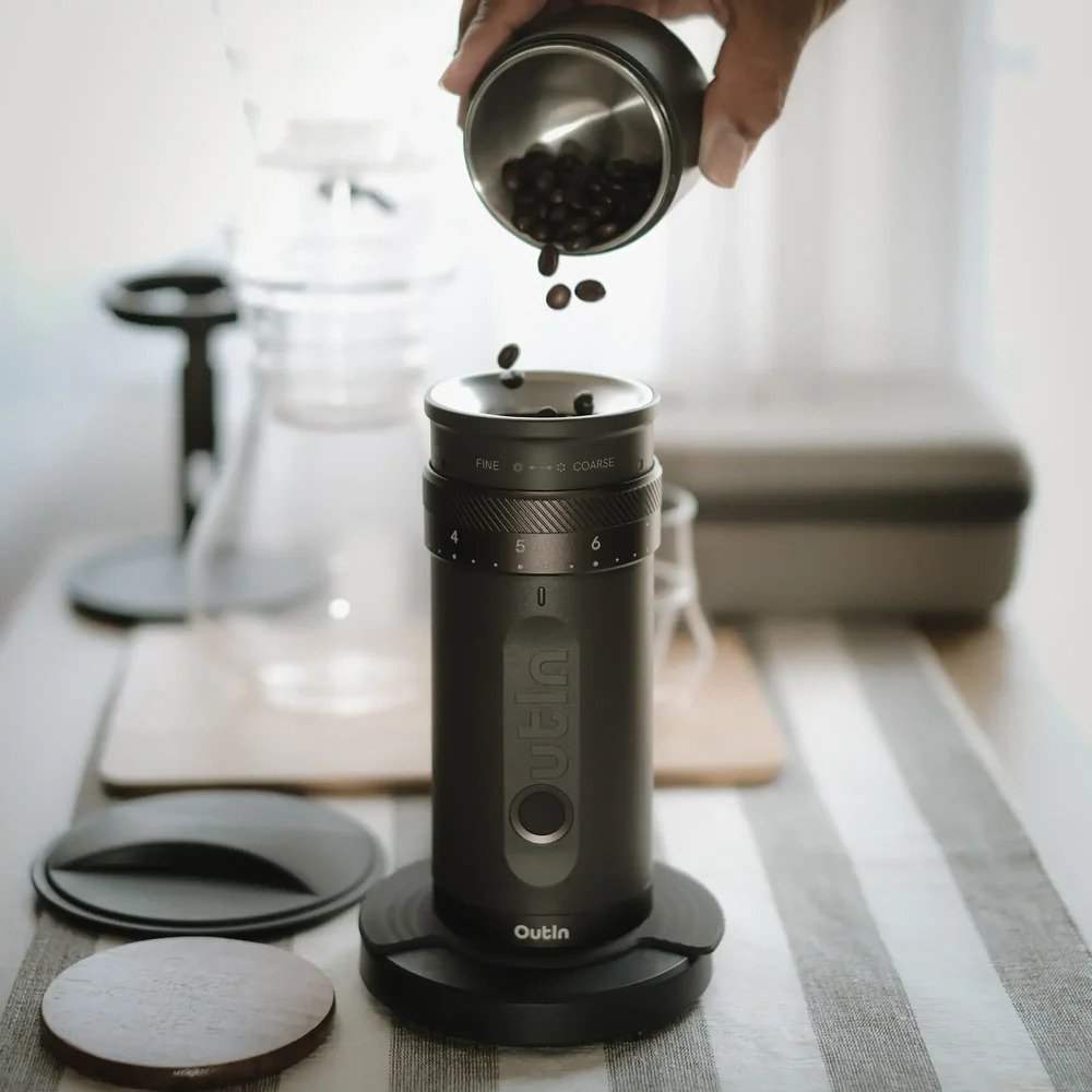Coffee seeds being poured into the OutIn portable electric coffee grinder for fresh grinding process