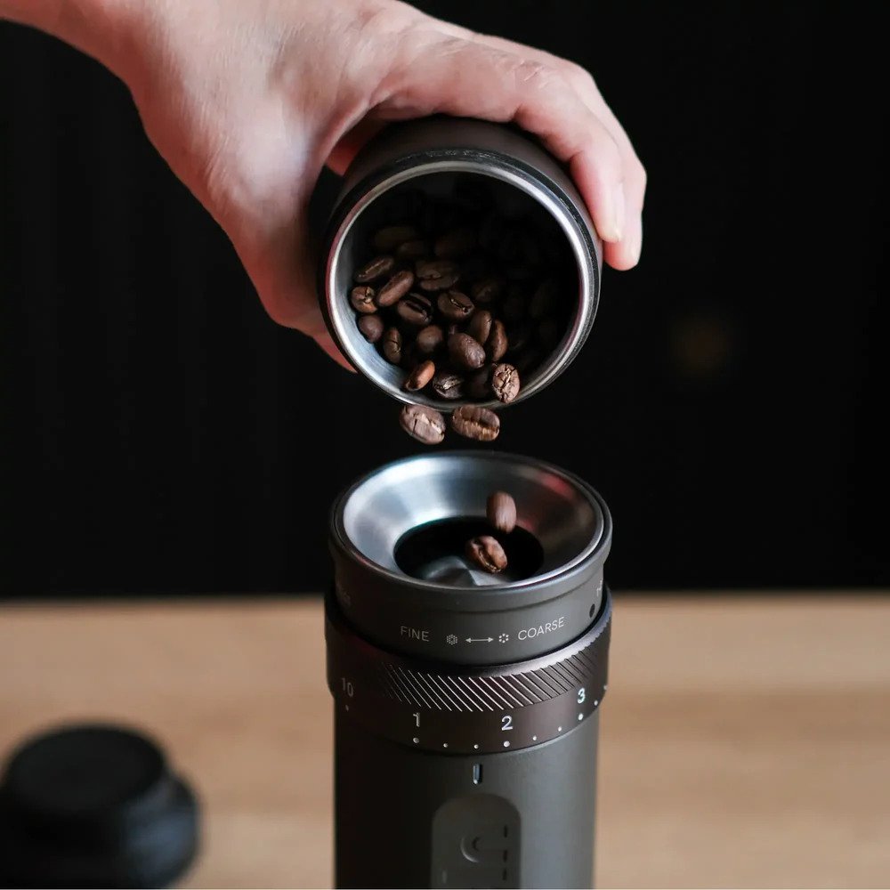 Coffee beans being poured into the OutIn portable electric coffee grinder for fresh grinding