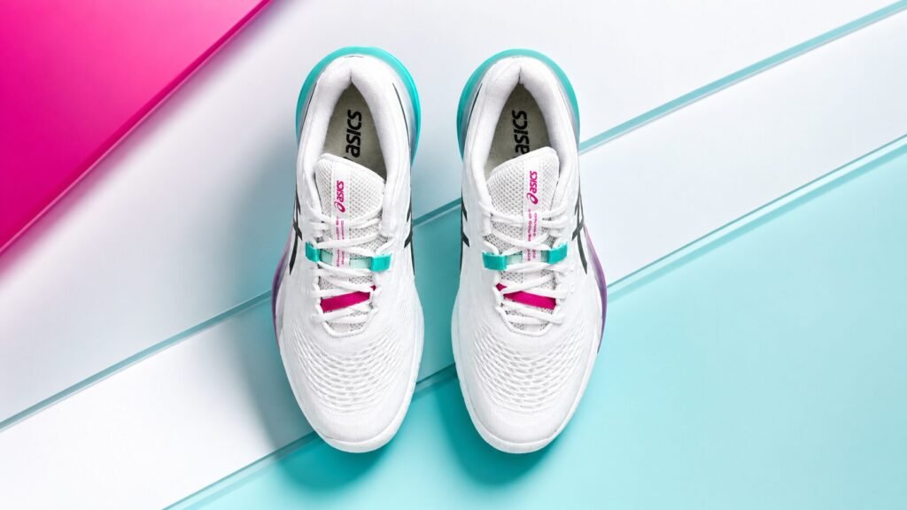 Top view of white Asics Gel Dedicate 8 tennis shoes with teal and pink accents on a clean modern background