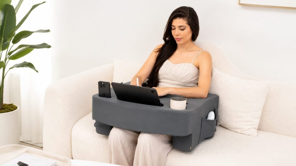 Grey TabCouchCaddy gaming reading pillow with XL lap desk, adjustable arm support, memory foam wrist rest, cup holder, phone holder, and storage pockets.